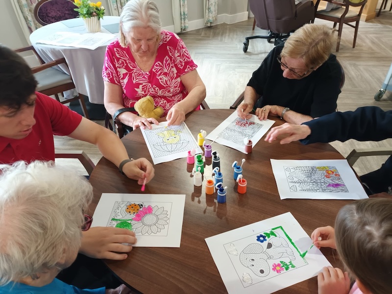group of residents sat around a table doing some painting on drawings