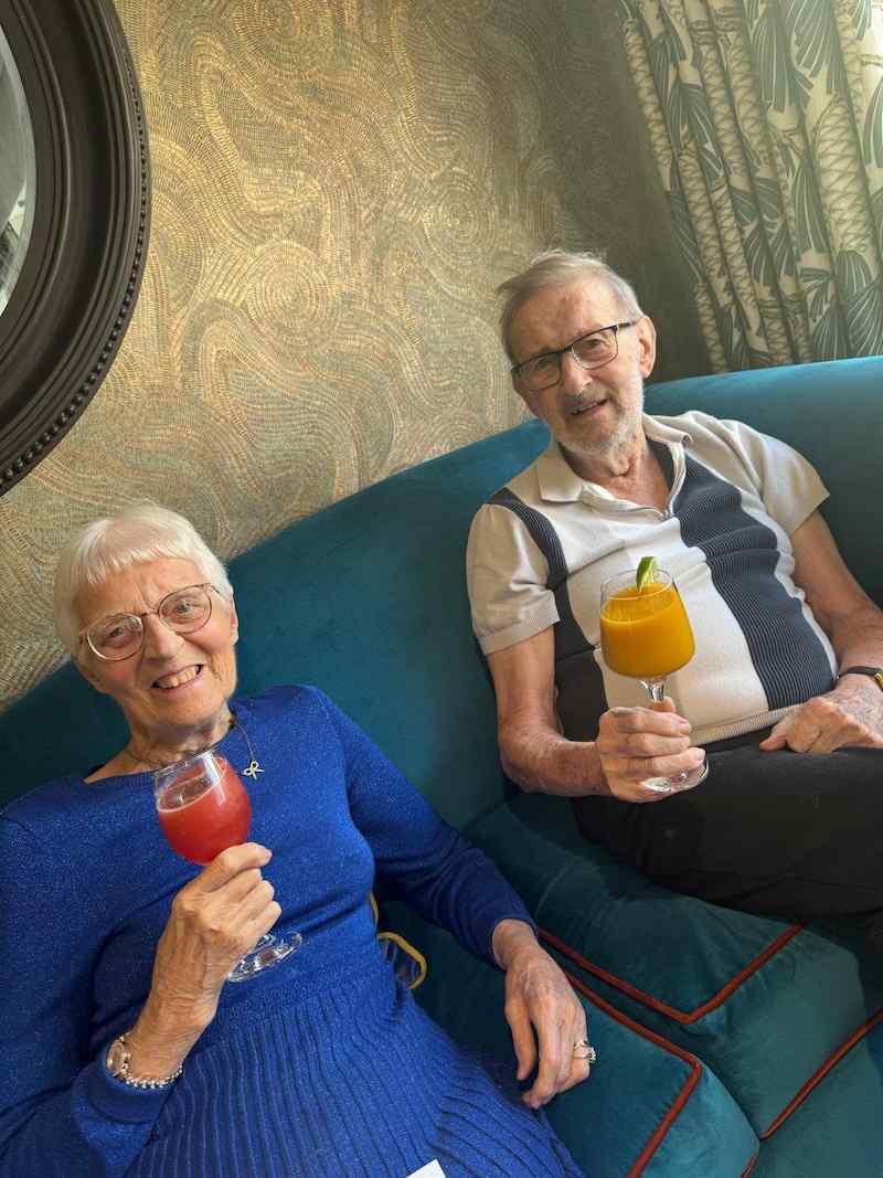 2 residents sat on the sofa enjoying smoothies in a glass