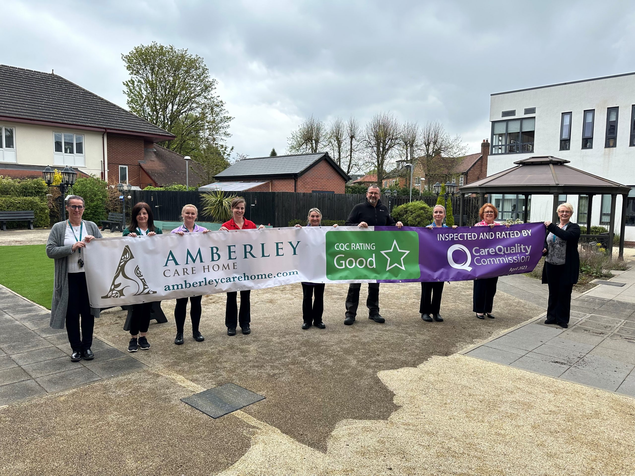 Our staff holding a banner of our CQC rating at Amberley Care Home
