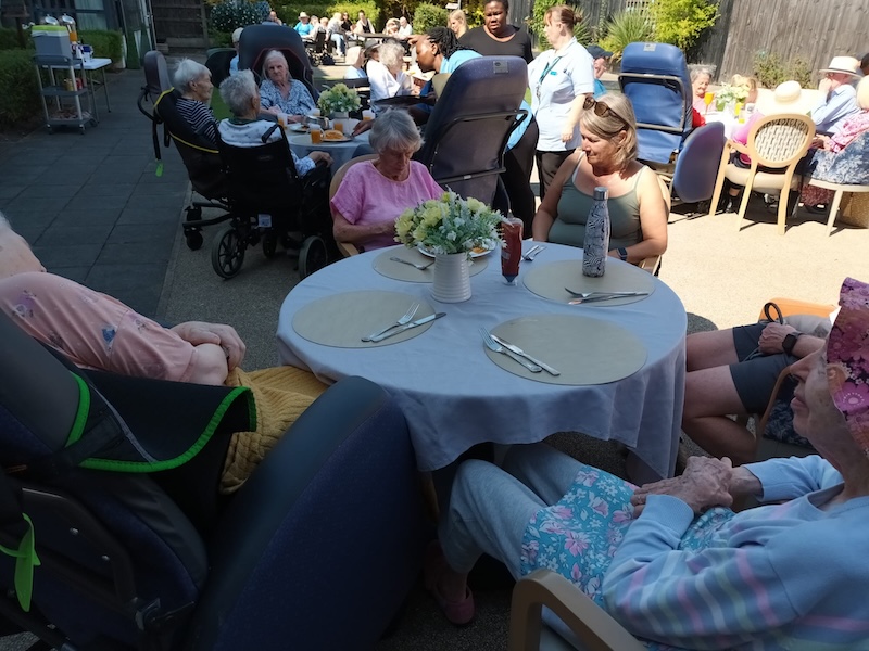 residents sat around a table outside with their loved ones