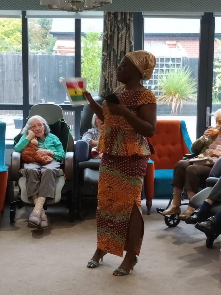 woman stood in traditional african attire holding up a flag