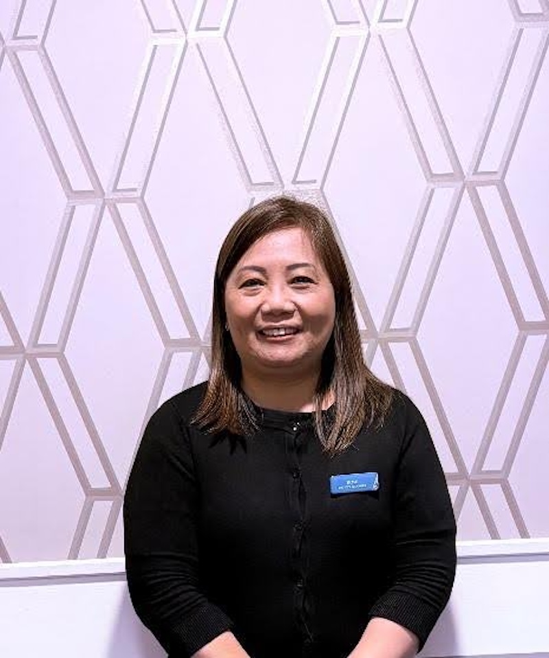 woman with brown hair stood smiling having a headshot taken for the team page