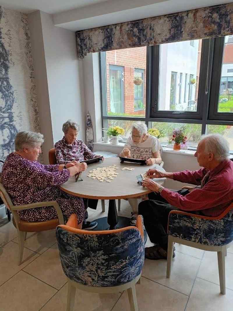 group of residents sat around a table playing dominoes